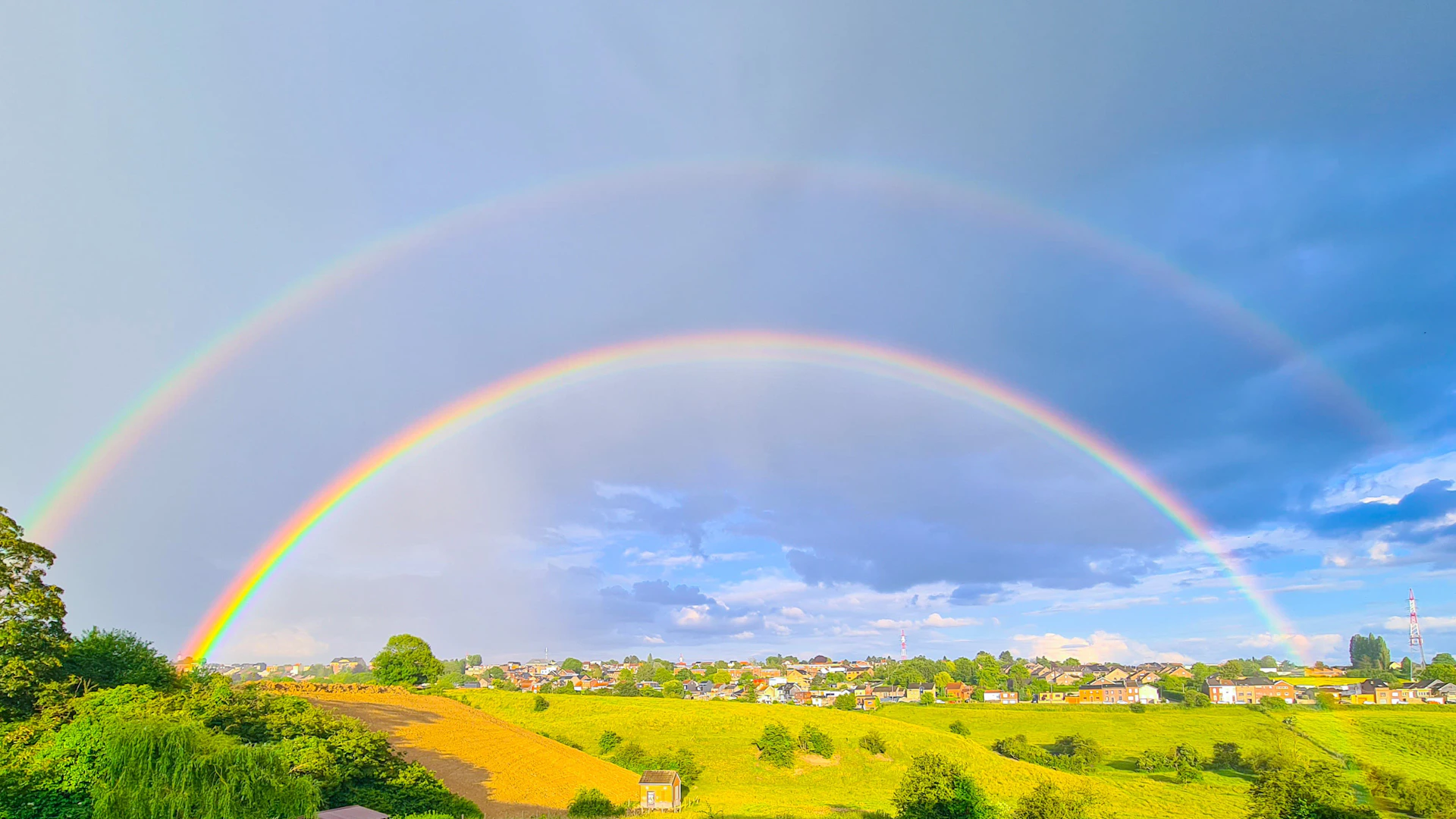 two rainbows in the sky over a green field