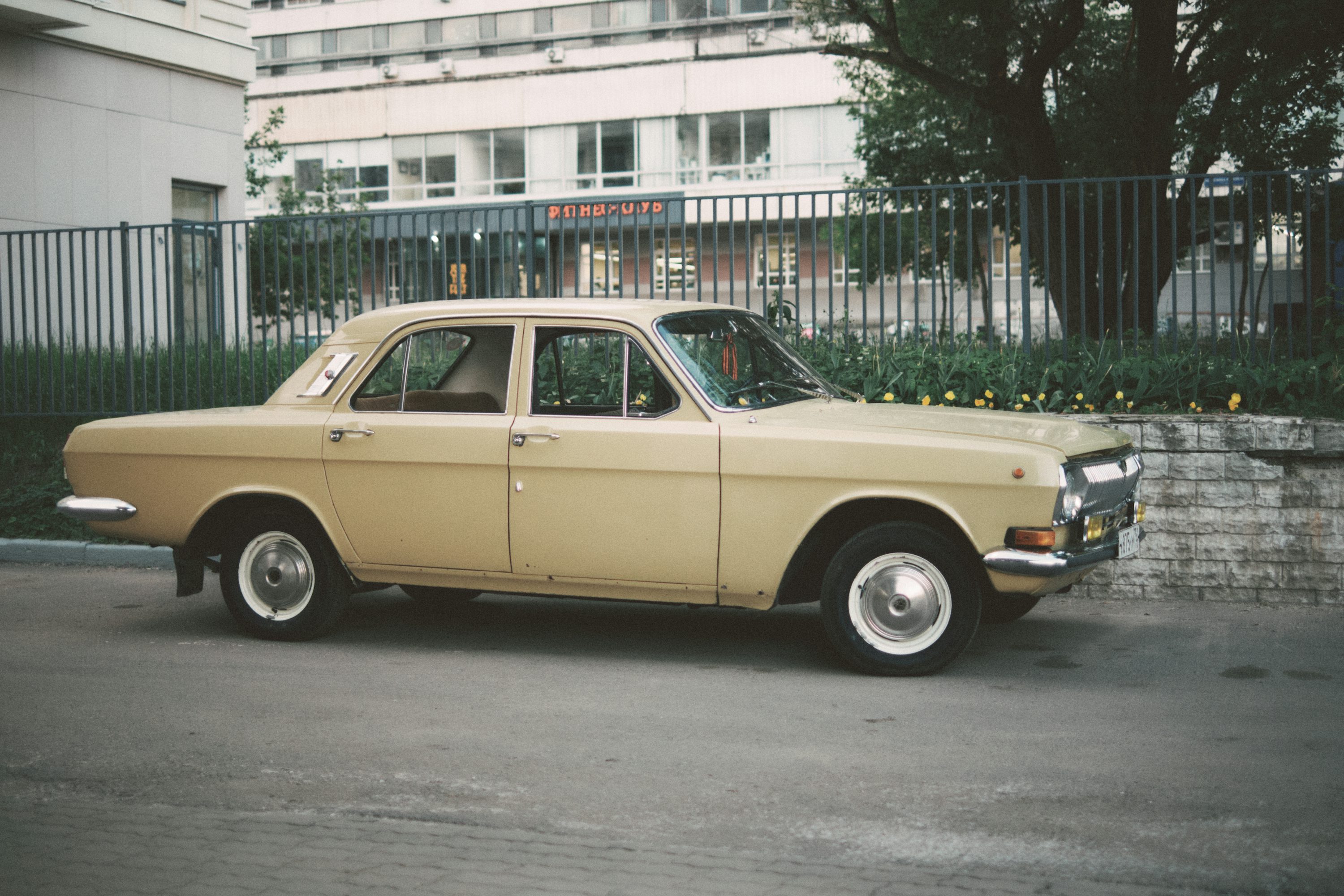 a tan car parked in front of a building