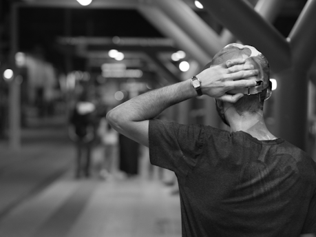 a man in a black shirt is covering his face with his hands