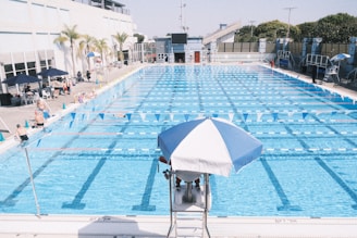 an empty swimming pool with a blue and white umbrella