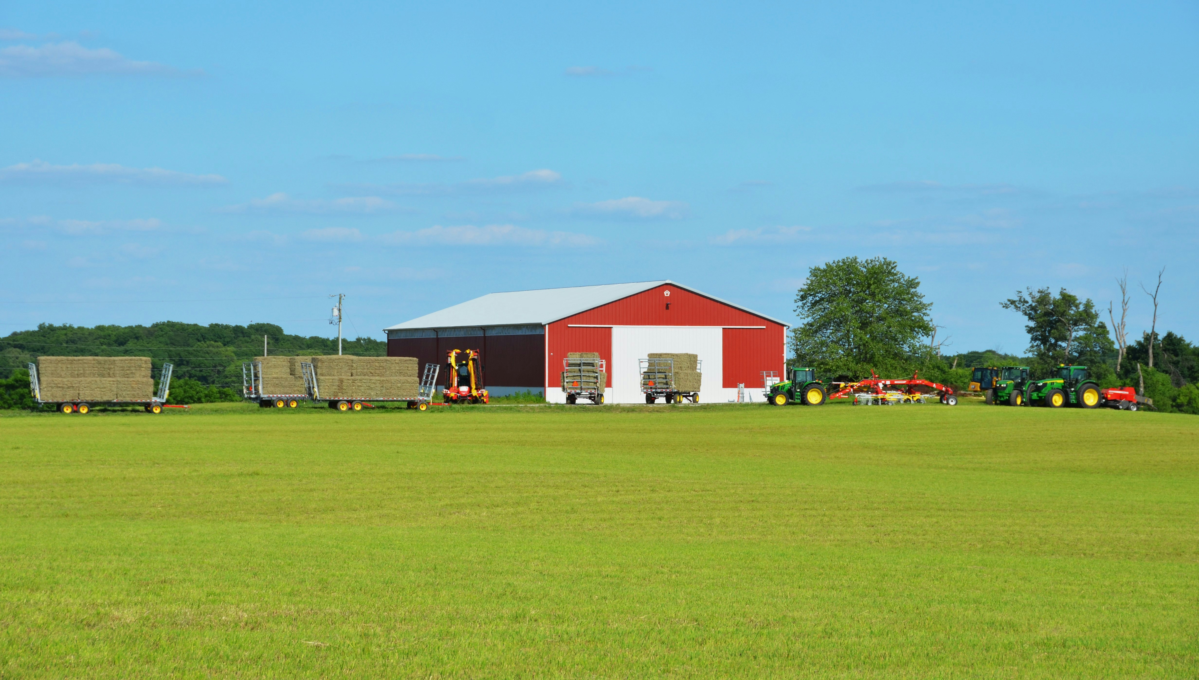 a farm with a red barn and tractor trailers
