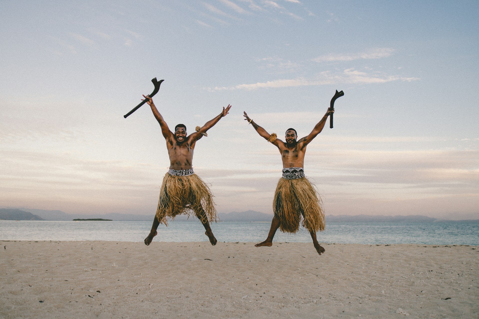 a couple of men standing on top of a sandy beach