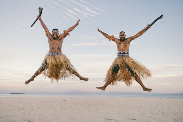 Two men in grass skirts jumping in the air — Fiji, Fiji