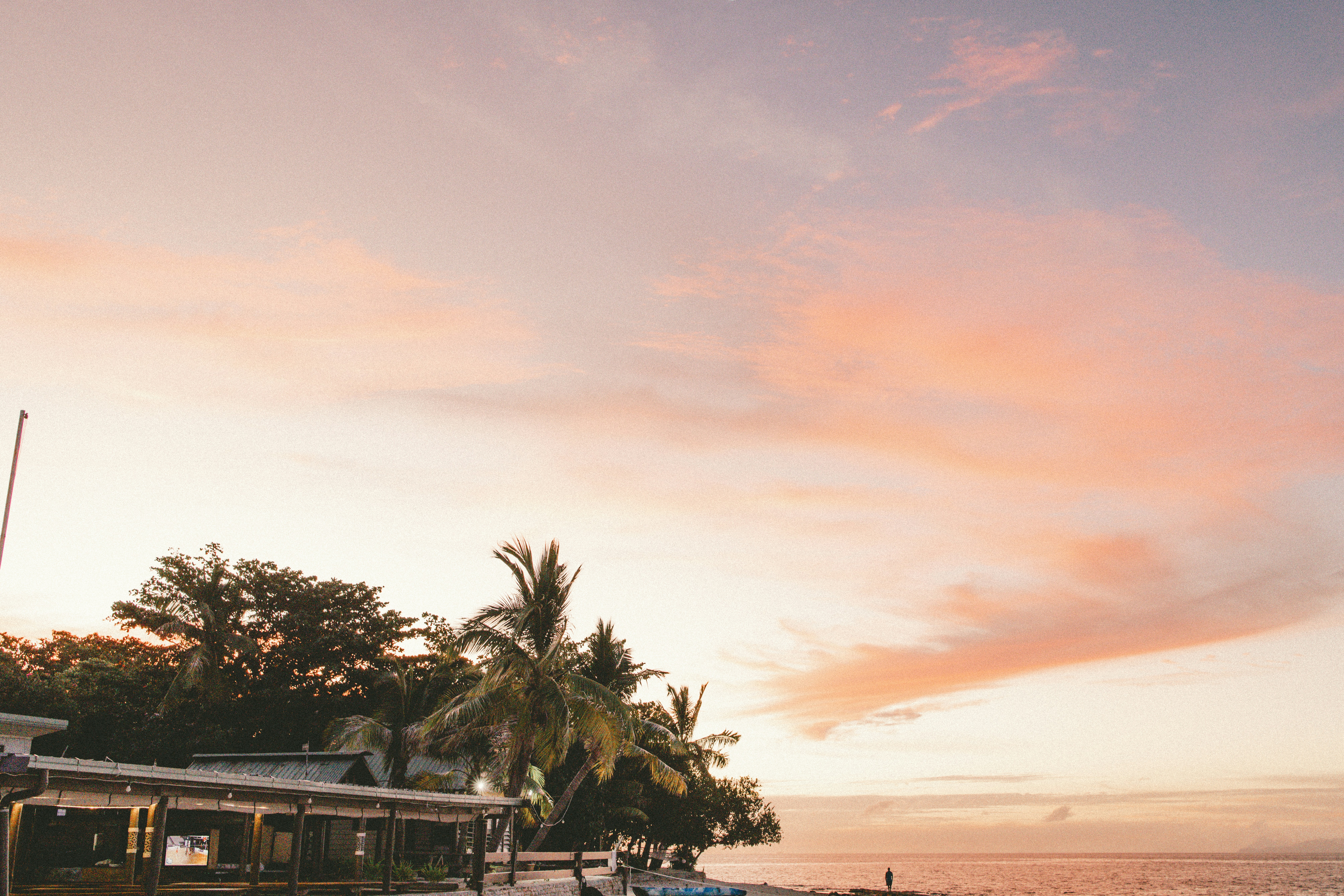 a boat is parked on the beach at sunset