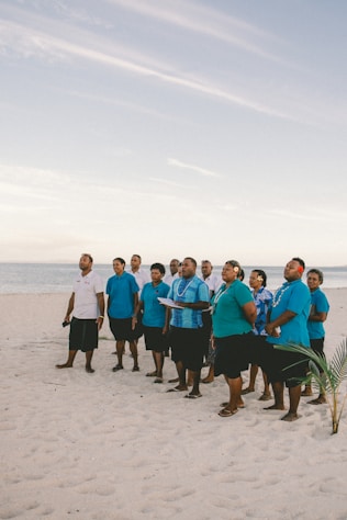 a group of men standing on top of a sandy beach