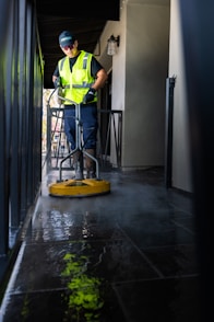 a man in a yellow vest is cleaning the floor