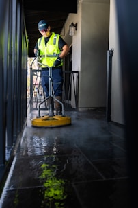 a man in a yellow vest is cleaning the floor