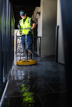 a man in a yellow vest is cleaning the floor