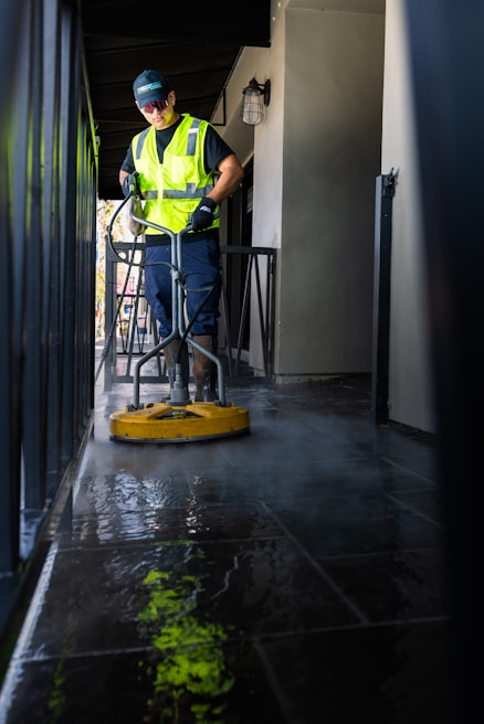 a man in a yellow vest is cleaning the floor