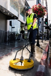 a man in a yellow vest is cleaning the street