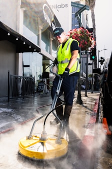 a man in a yellow vest is cleaning the street