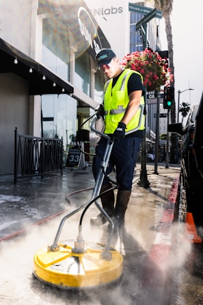 a man in a yellow vest is cleaning the street