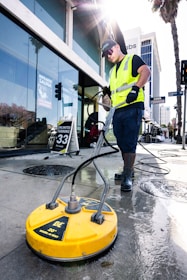 a man in a yellow vest is cleaning the street
