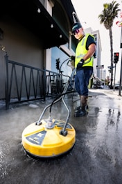 a man in a yellow vest is cleaning the street