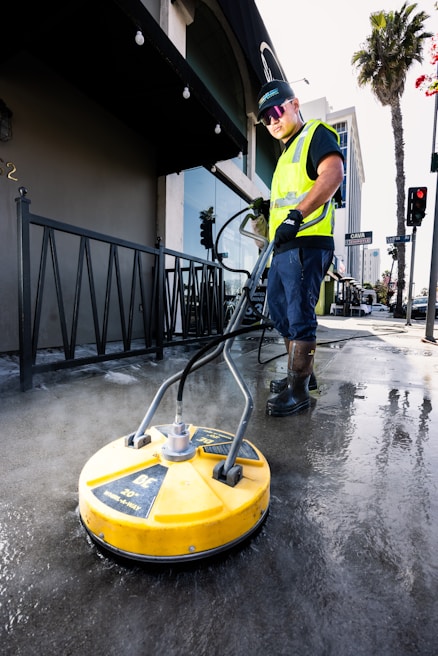 a man in a yellow vest is cleaning the street