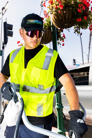 a man wearing a safety vest and holding a hose