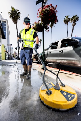 a man in a yellow vest is cleaning the street