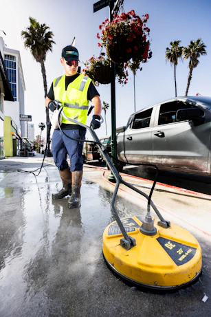 a man in a yellow vest is cleaning the street