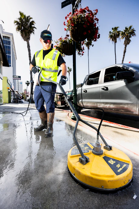 a man in a yellow vest is cleaning the street