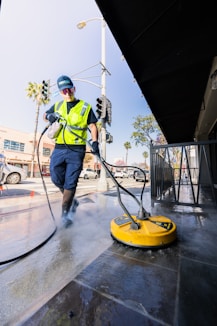 a man in a yellow vest is cleaning a street