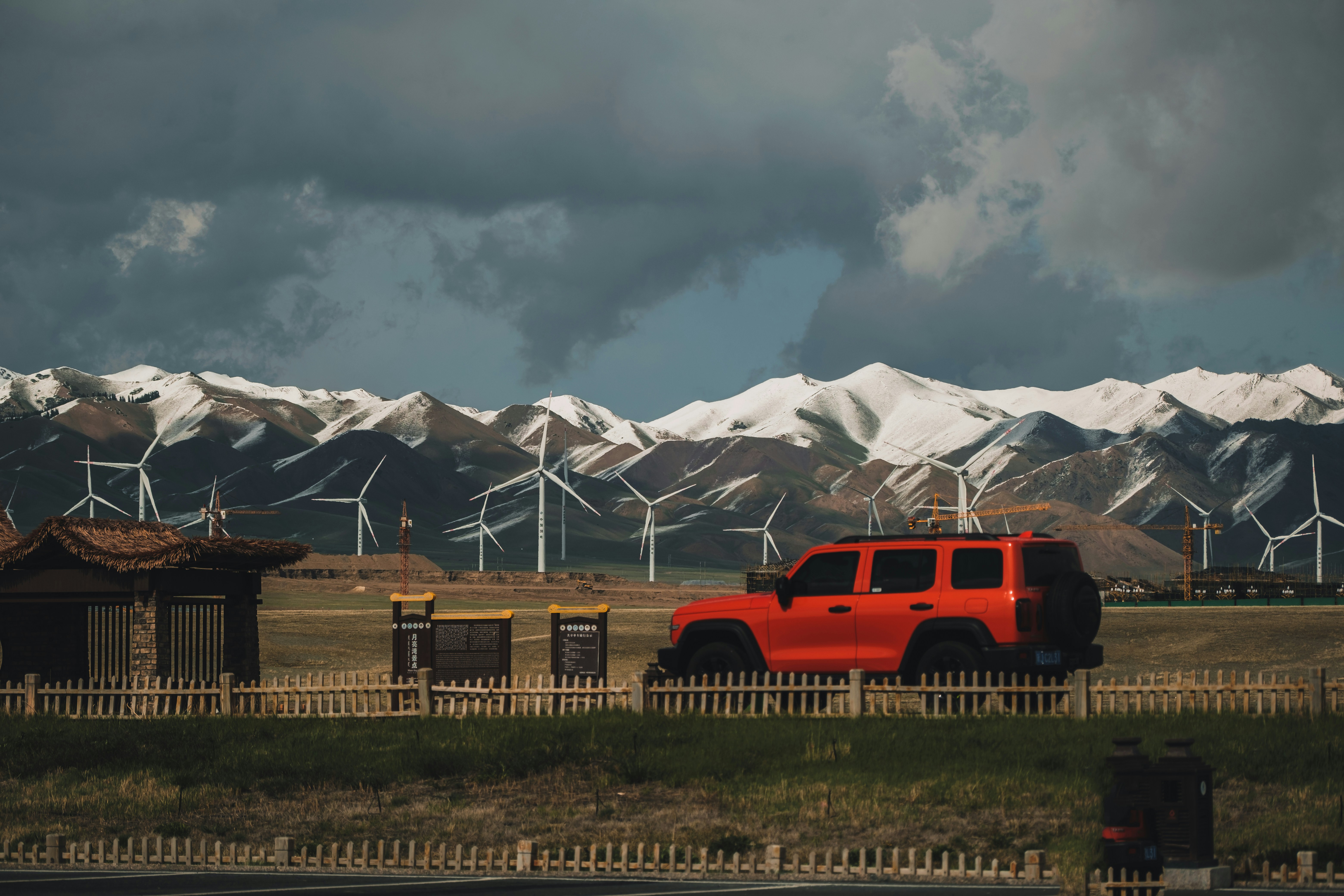 a red truck driving down a road next to a wind farm