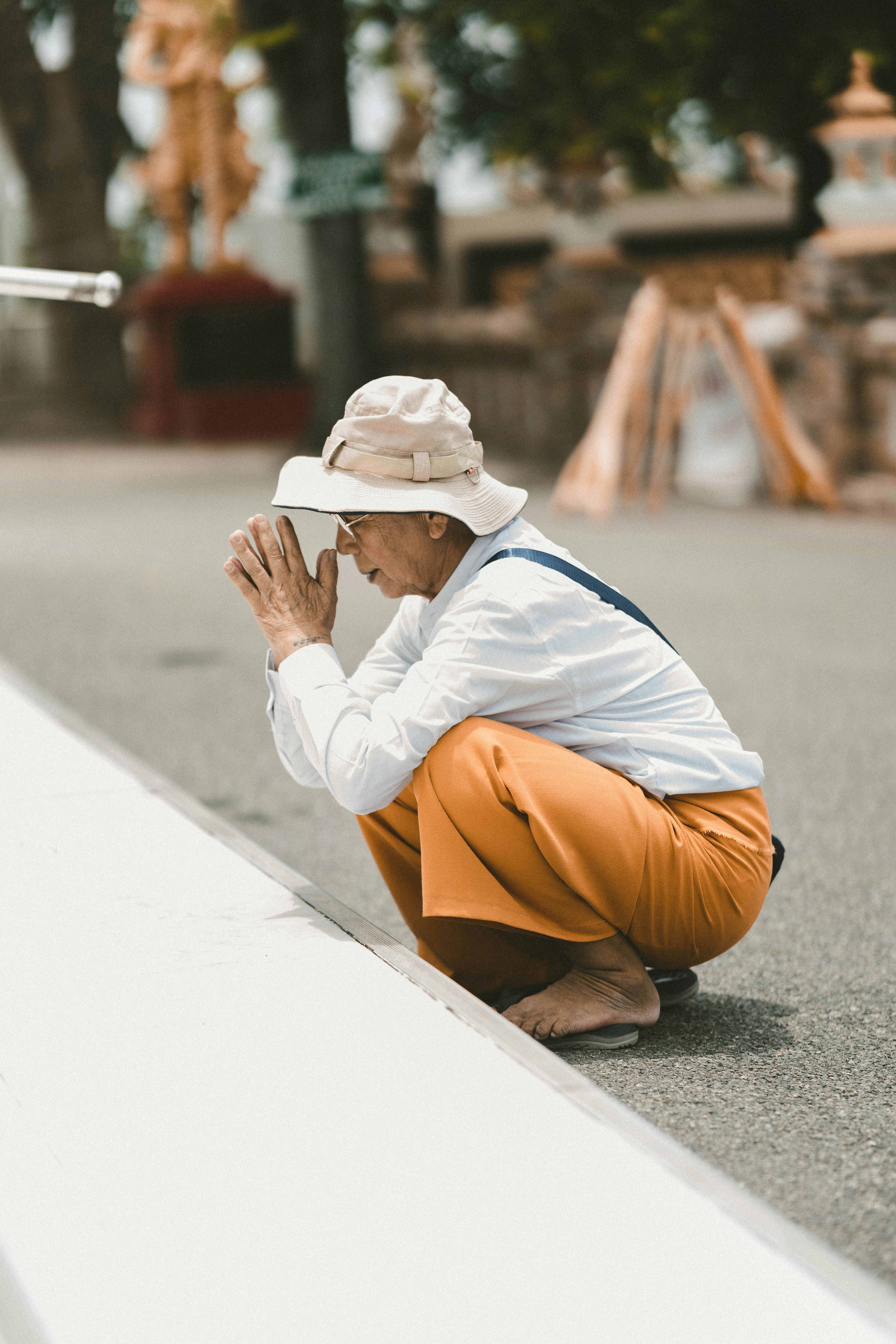 a man sitting on the ground with his hands together