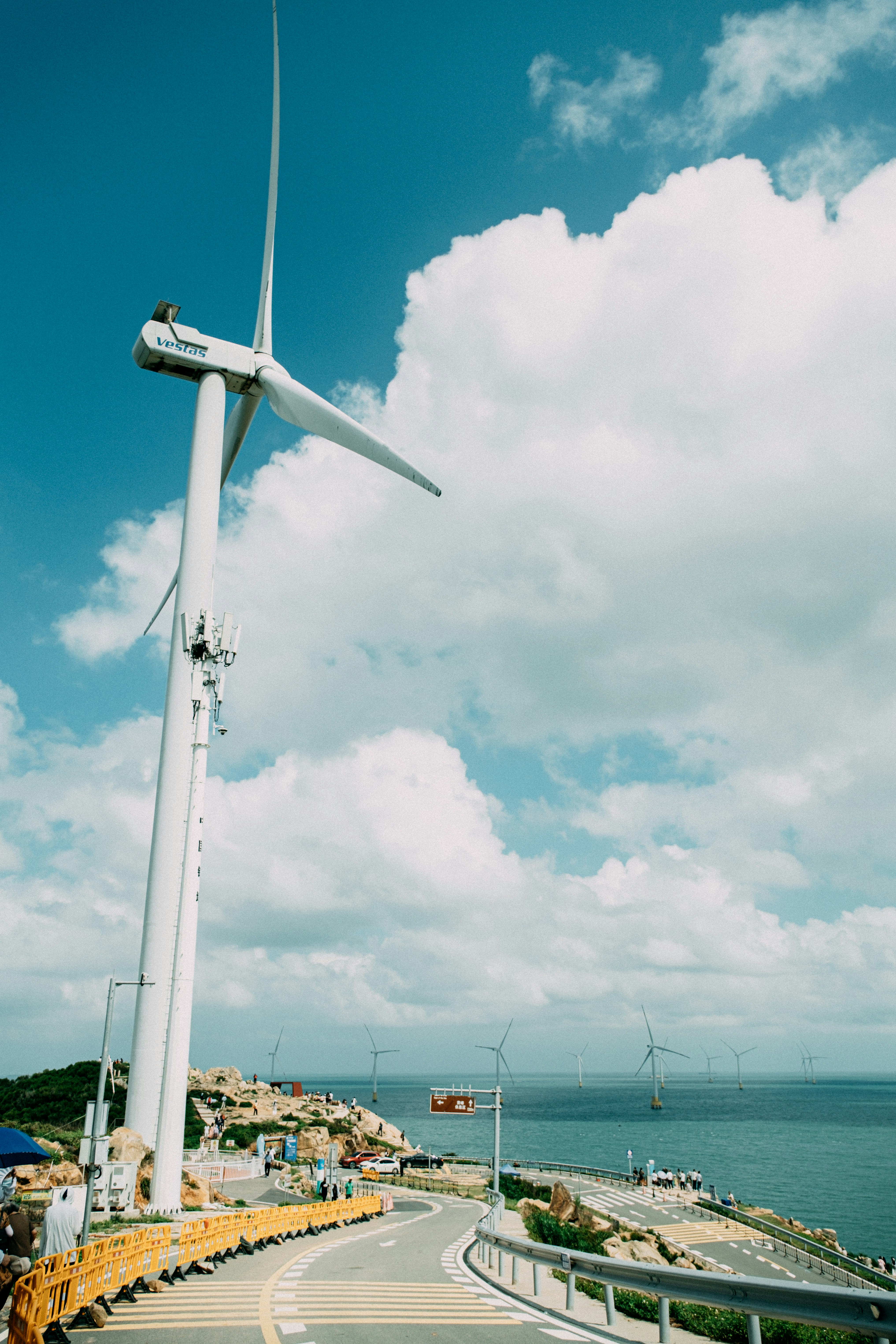 a wind turbine on the side of a road next to the ocean