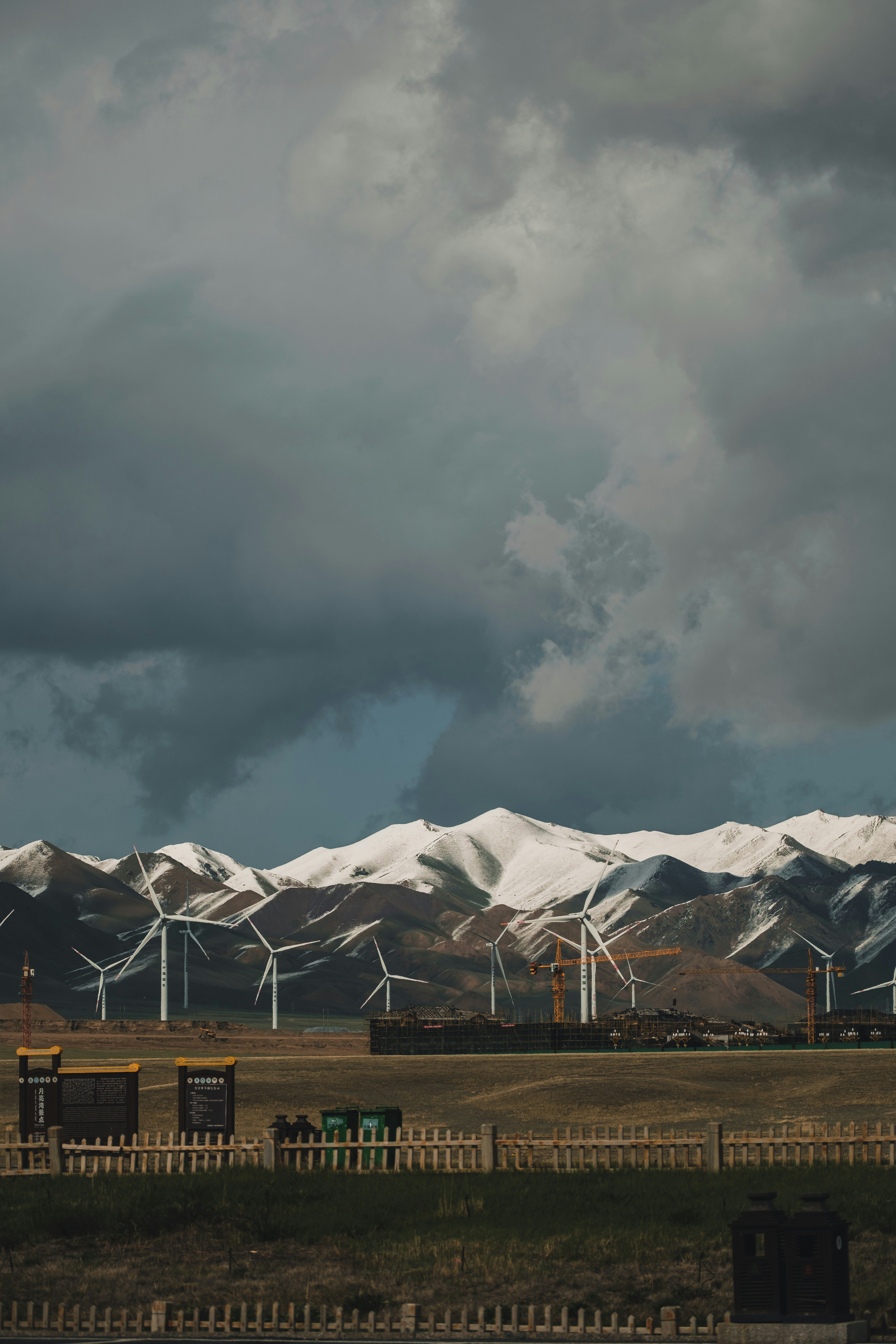 a wind farm with snow covered mountains in the background