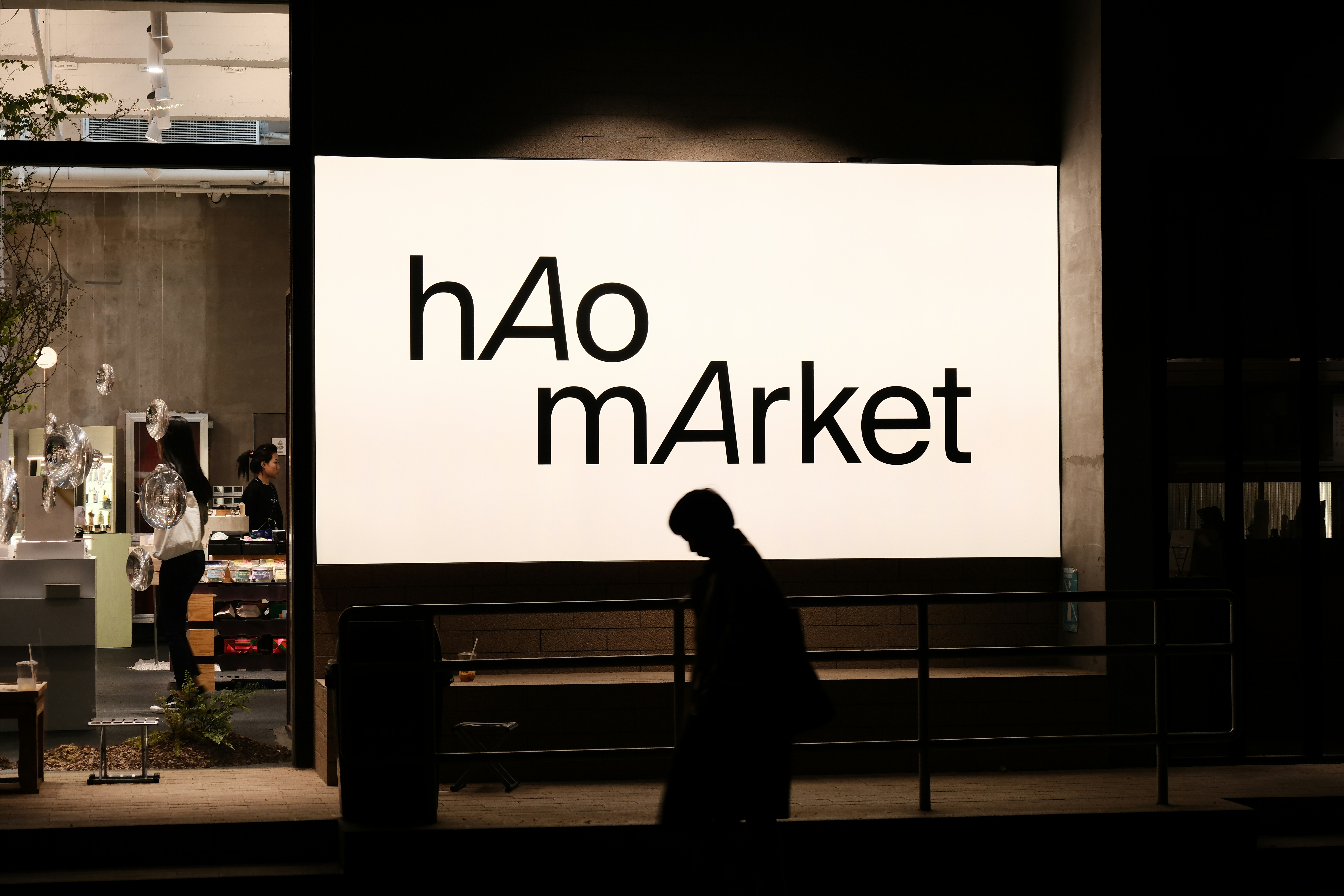 a person standing in front of a sign that says hao market