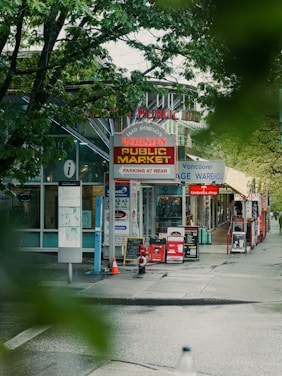 a city street with a public market on the corner