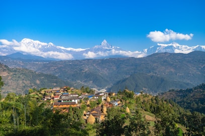 a small village on a hill with mountains in the background