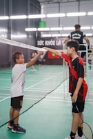 two young boys are playing tennis on a court