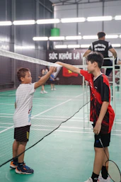 two young boys are playing tennis on a court