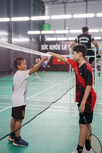 two young boys are playing tennis on a court