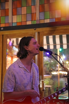 a man playing a guitar and singing into a microphone
