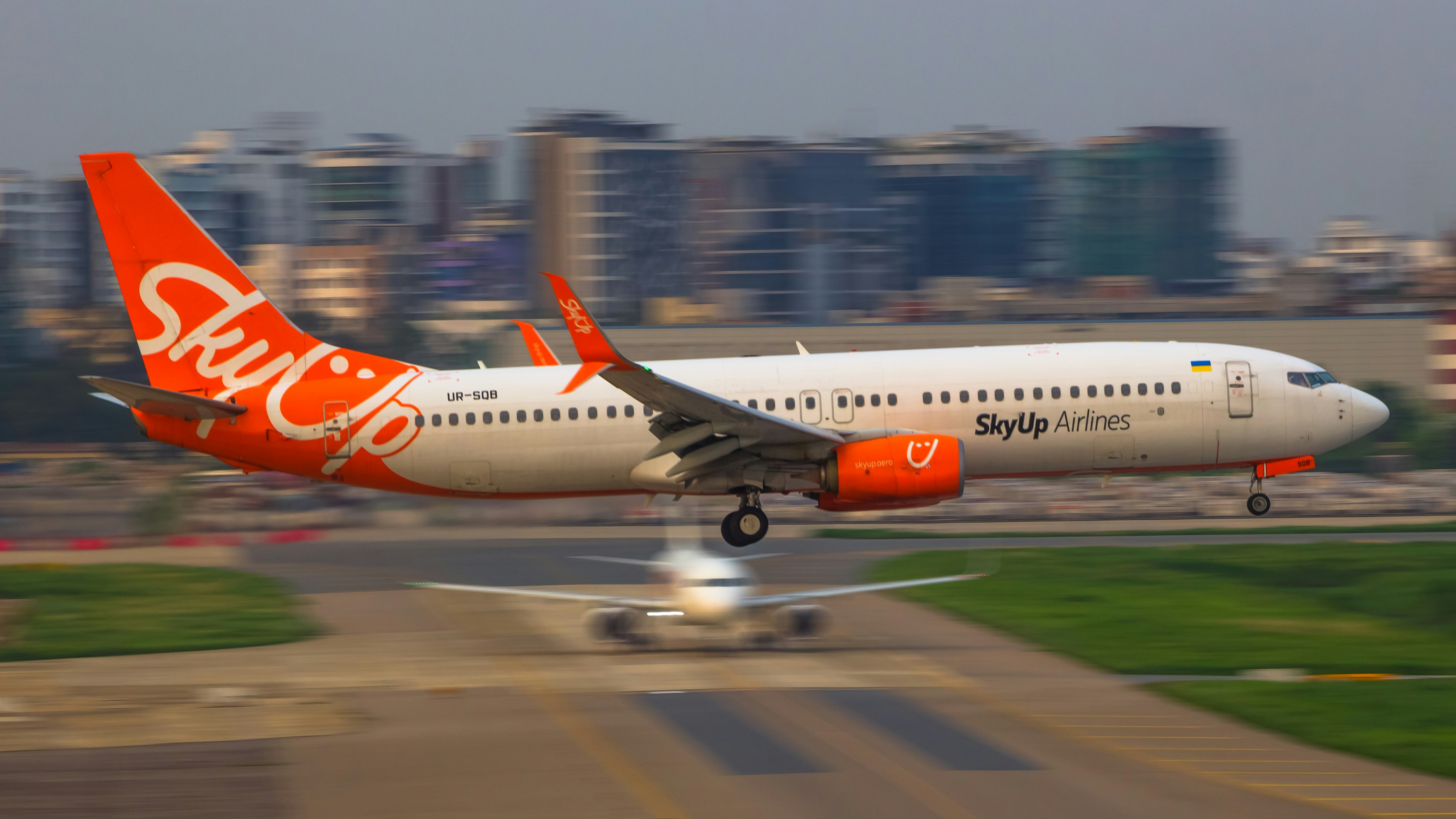 pesawat jet oranye dan putih lepas landas dari landasan pacu bandara