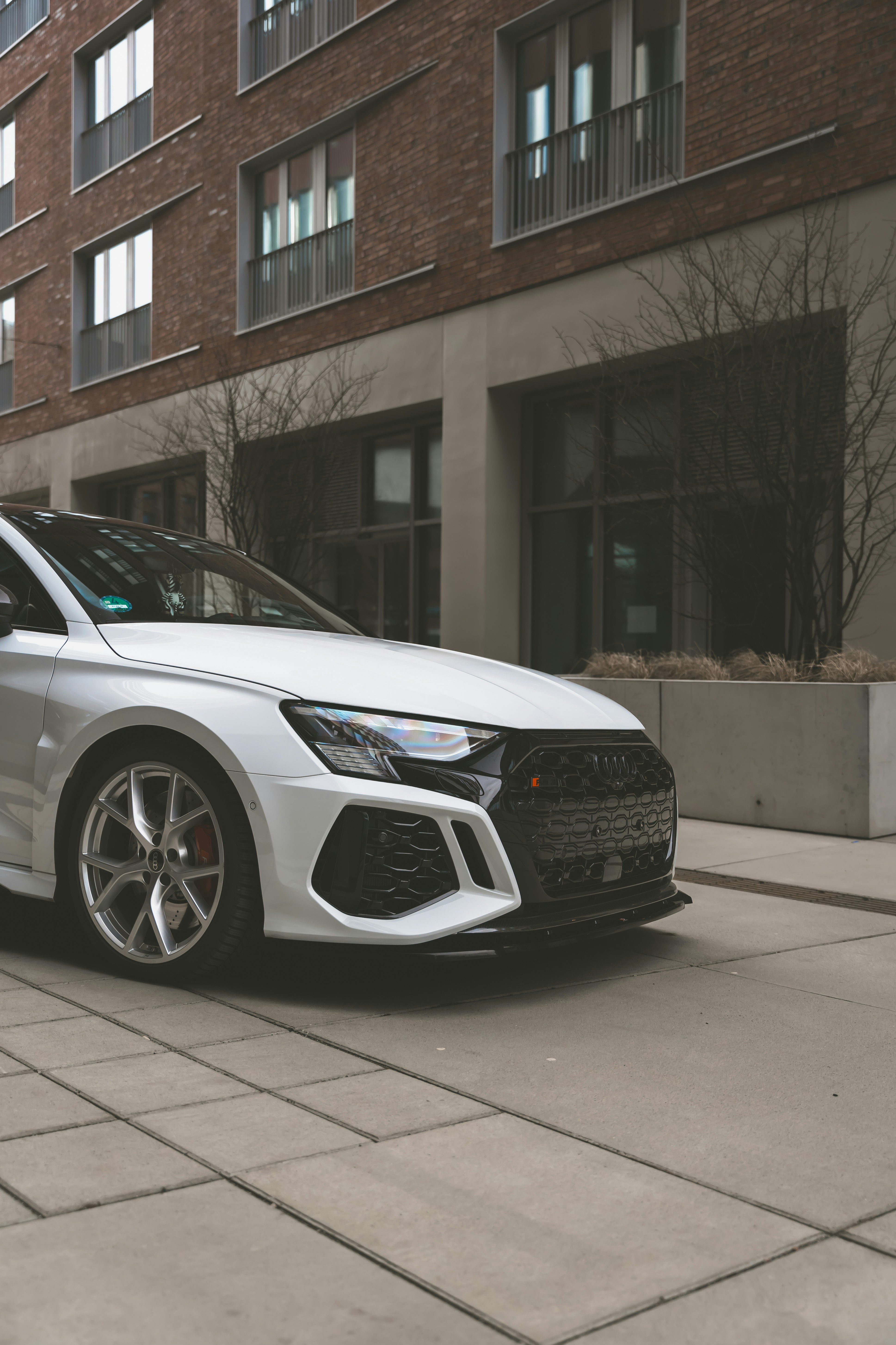 Un coche blanco aparcado frente a un edificio alto