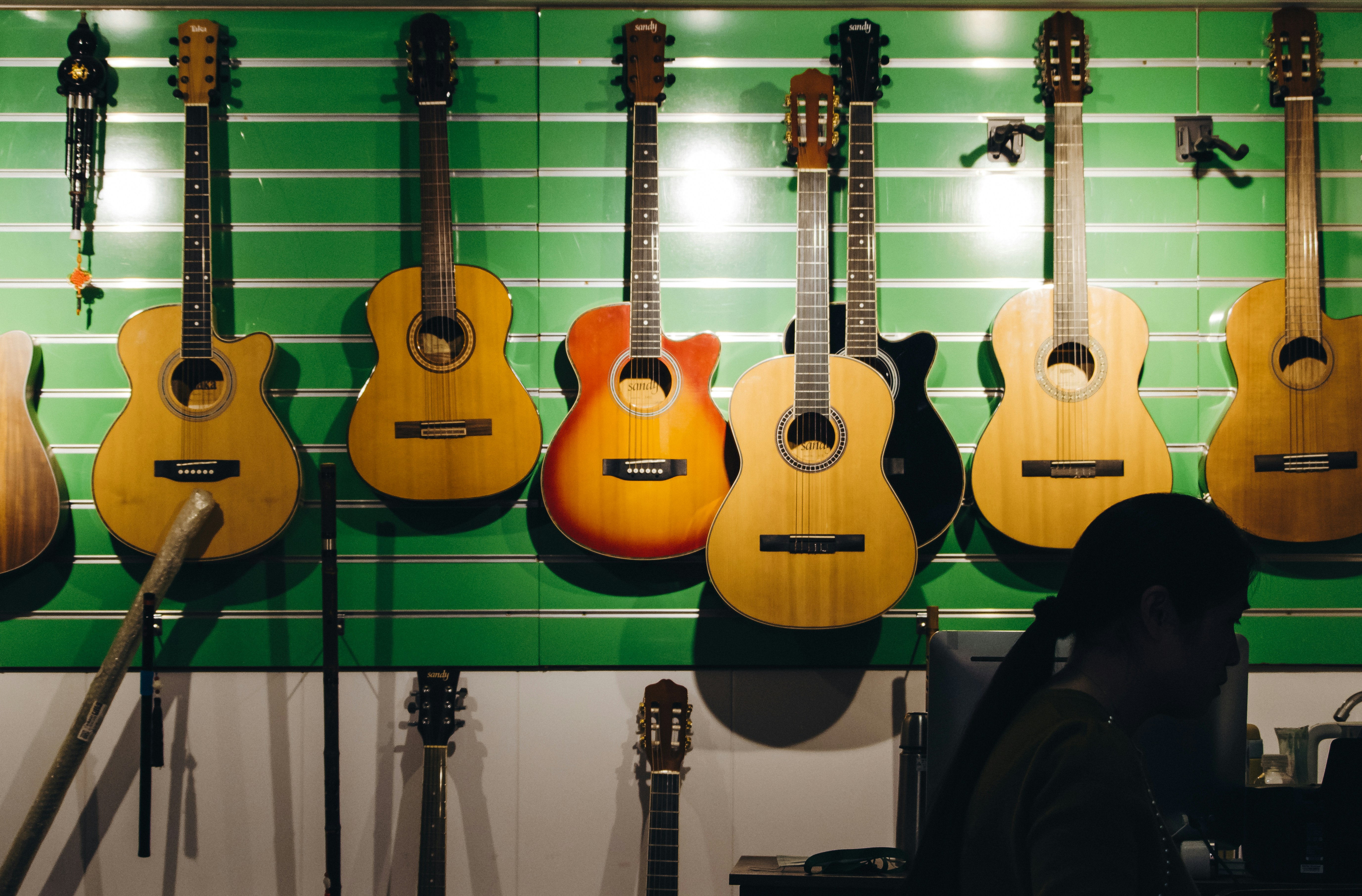 a man sitting in front of a wall of guitars