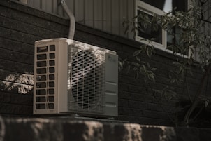 a white air conditioner sitting on top of a brick wall