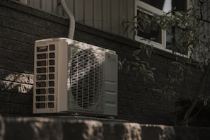 a white air conditioner sitting on top of a brick wall