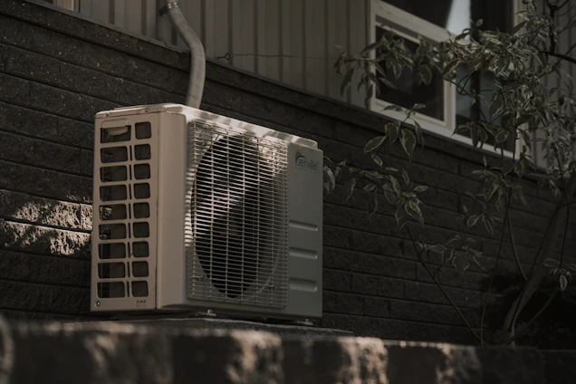 a white air conditioner sitting on top of a brick wall