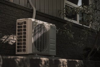 a white air conditioner sitting on top of a brick wall