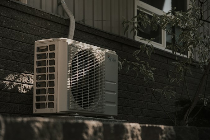 An outdoor air conditioning unit against a brick wall, the kind of equipment Las Vegas homeowners should have serviced before next summer