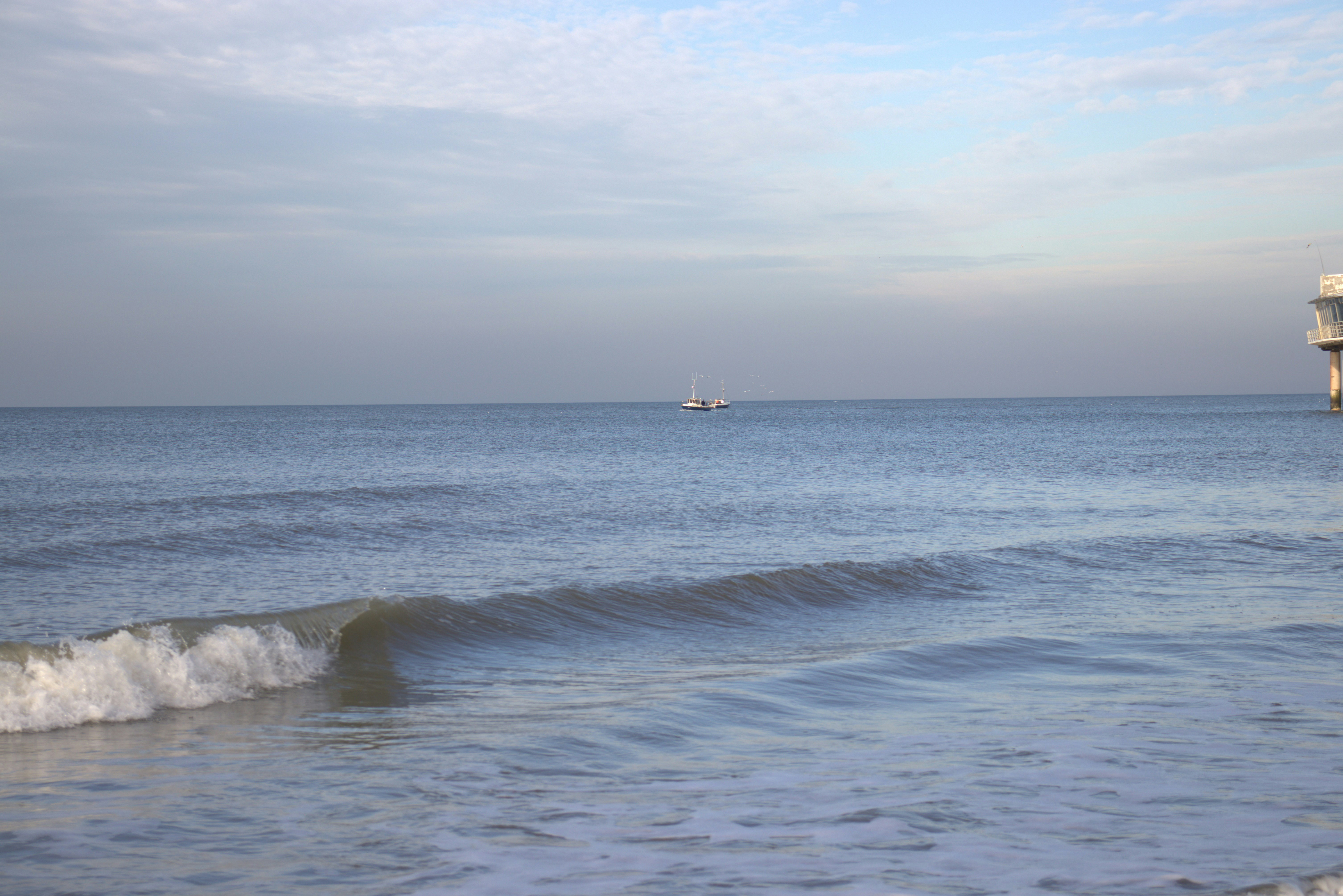 a boat is out in the ocean near a pier