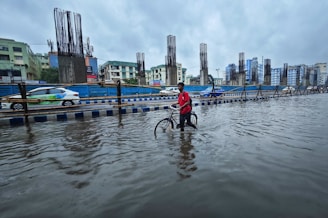 a person standing in a flooded street with a bike