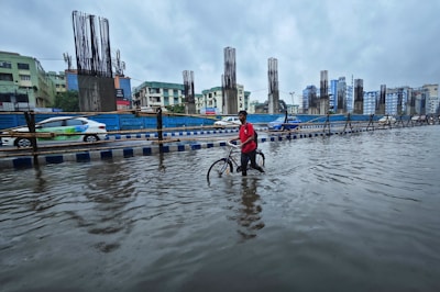 a person standing in a flooded street with a bike
