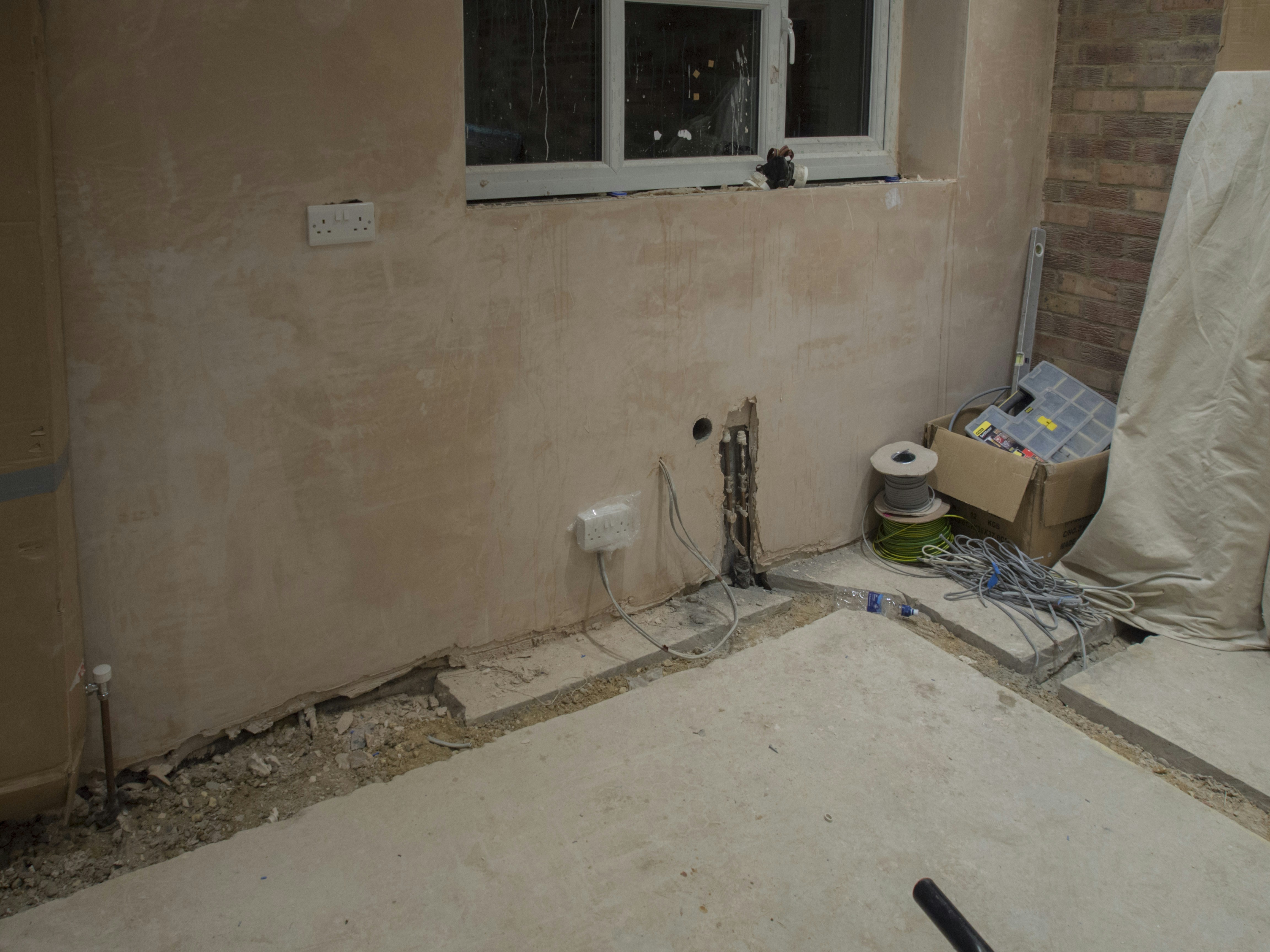 Dated home interior under construction, exposed framing, dim construction lighting, rough unfinished walls and floors