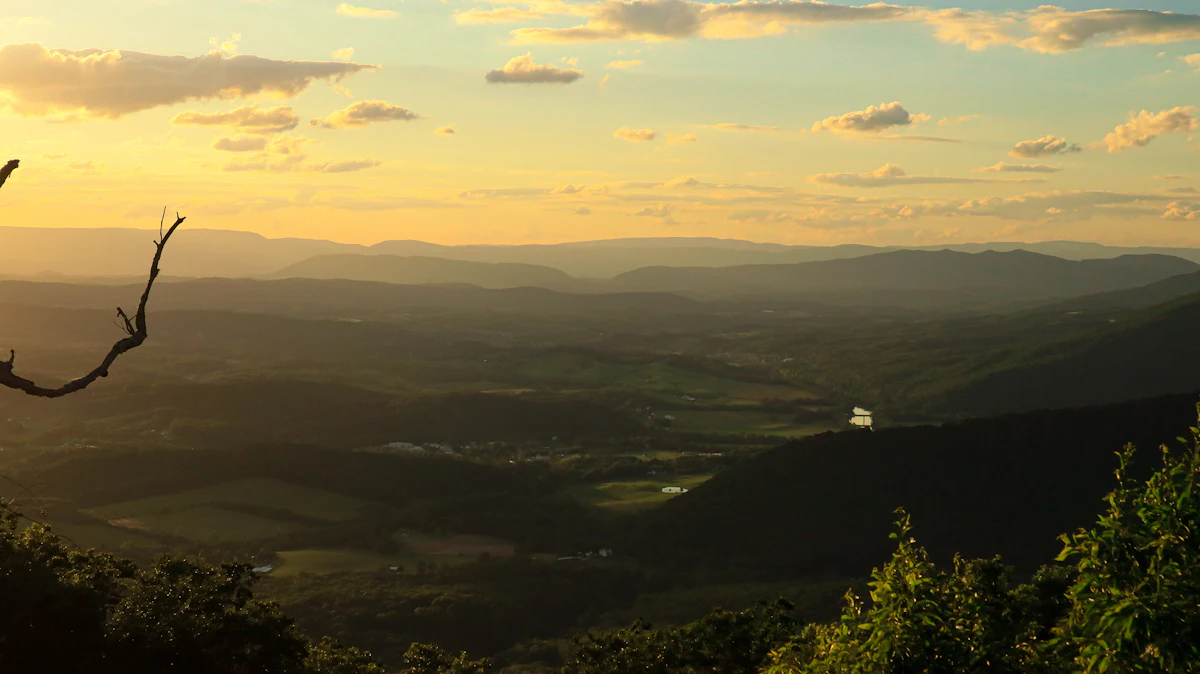 Evening sun over a wide valley seen from a wooded ridge on the Blue Ridge Parkway