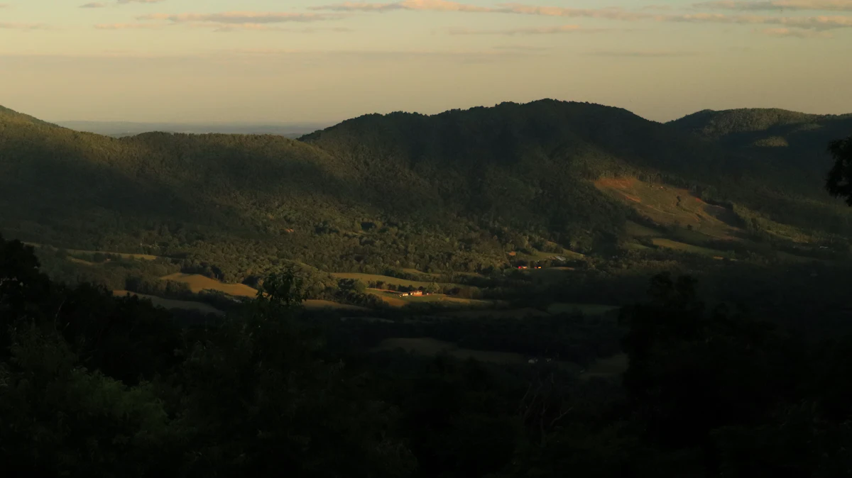 Low evening light on a forested ridge above farm fields, seen from the Blue Ridge Parkway