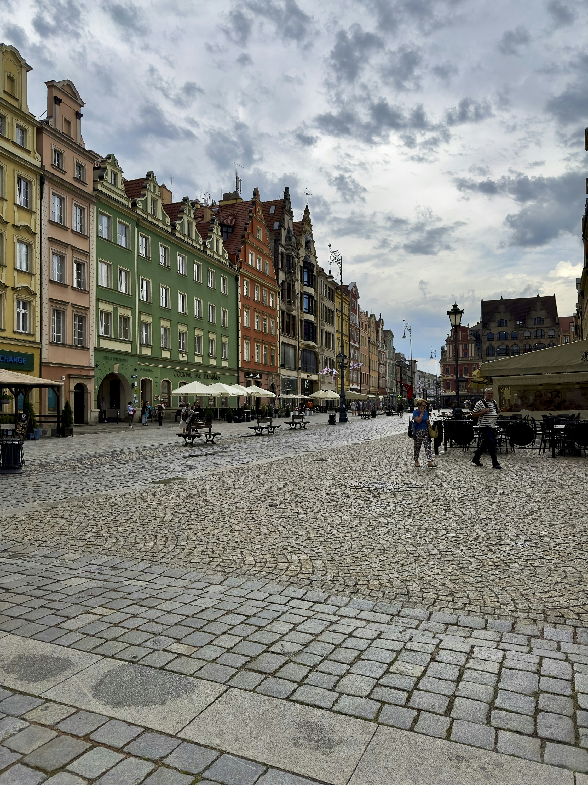 Charming European cobblestone street with colorful buildings and outdoor cafes at golden hour